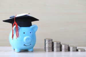 piggy bank with a graduation cap and quarters stacking next to them