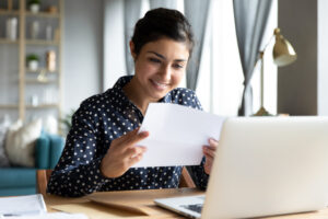 women reading a letter in front of a laptop