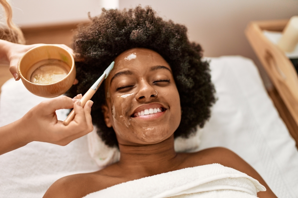 Young african american woman smiling confident having facial treatment at beauty center